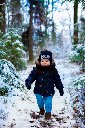 Little boy walking in the winter forestの写真素材