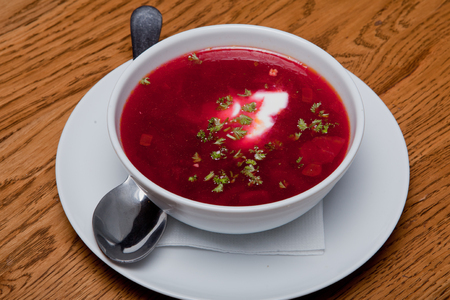 Red Ukrainian borsch with sour cream in a plate is on the table. Close-up, selective focus.の写真素材