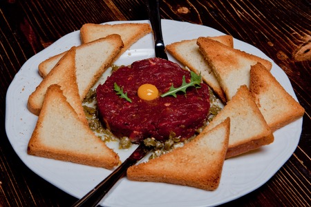 Fried tartar meat dish with yolk and a crown on a black wooden backgroundの写真素材