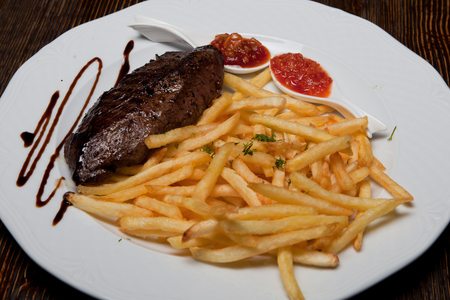 juicy beef steak with french fries with sauce on a plateの写真素材
