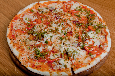 Home pizza on a wooden table. Ingredients of pizza - Mozzarella, Bulgarian pepper, tomatoes, champignons, Crimean onion, string beans, oregano, greensの写真素材