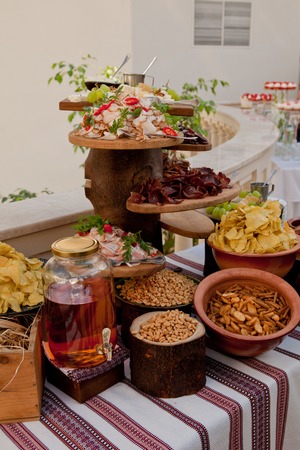 Delicious wedding reception table with snacks, peanuts, crackers, chips, basturma, fat and moonshine on the Cossack tableの写真素材