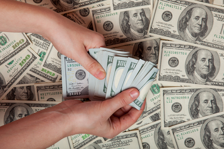 Cash in hand. Profit, savings. Stack of dollars. a person who is counting money against the background of money, success, motivation, financial flows, wealth. Buy dollars, dollars manually.の写真素材