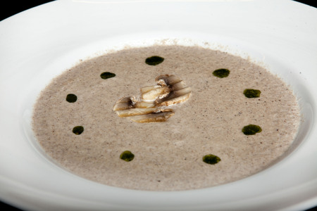 Mushroom cream soup on a white plate on a black background.の写真素材