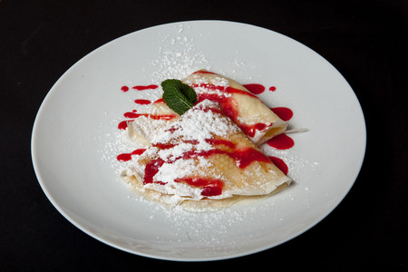 Pancakes with cheese on a white plate on a black background.の写真素材