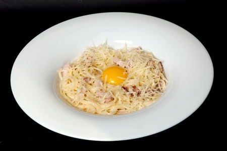 Italian cuisine, egg pouch, spaghetti, carbonate paste on a black background.の写真素材