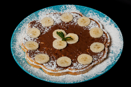 waffles with chocolate and banana on a black background.の写真素材