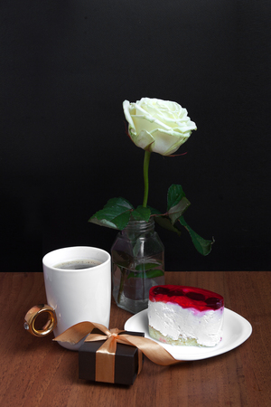 A cup of coffee with a cake and a rose on a black background. Valentine's Day.の写真素材