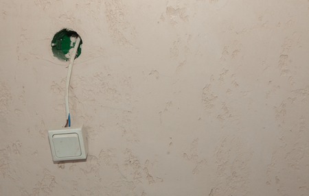 An electric switch hangs on a wire on the wallの写真素材