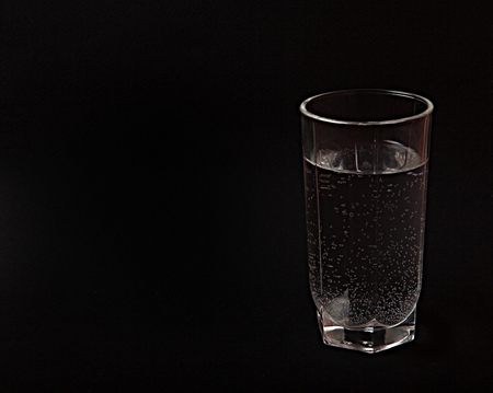 a glass of water on a black background, a place for the textの写真素材