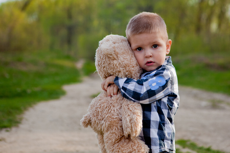 Boy in a park with a teddy bear.の写真素材