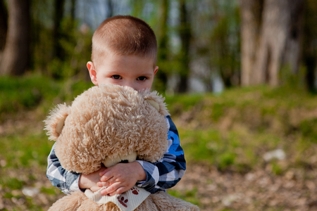 Boy in a park with a teddy bear.の写真素材