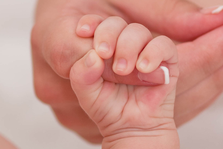 Mother holding newborn baby's hand, the hand of the newborn is holding mom's fingerの写真素材