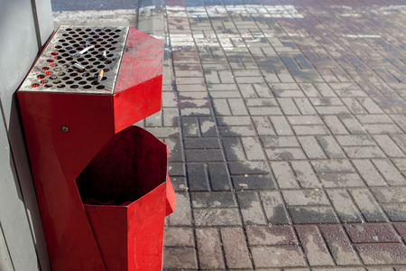 Street trash can with ashtray and cigarette butts. Trash can tied to the fence.の写真素材