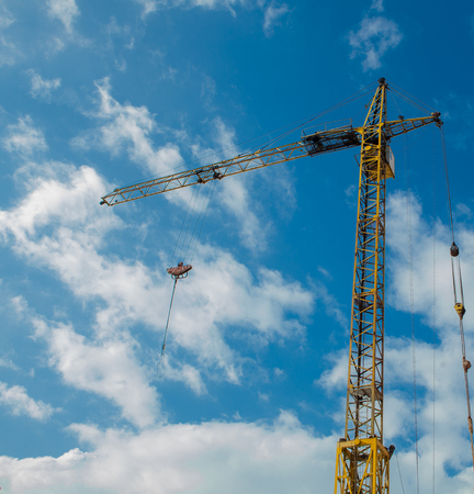 Industrial background with construction crane over blue cloudy sky.の写真素材