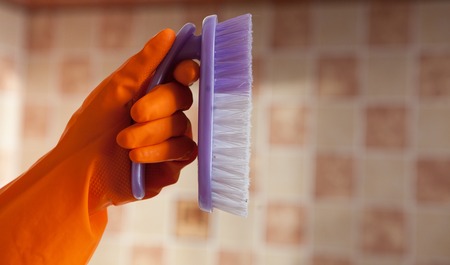 Brush cleaning in hand, isolated against the background of the tile.の写真素材