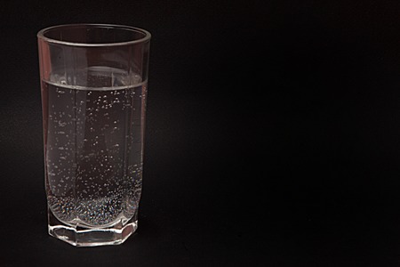 a glass of water on a black background, a place for the textの写真素材