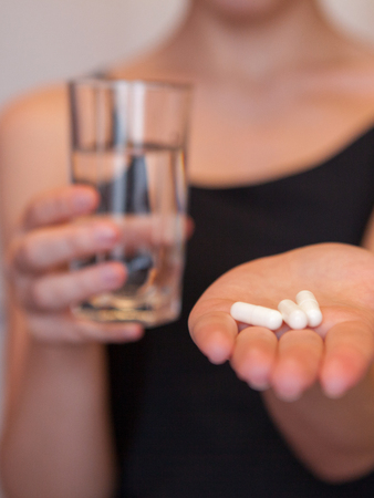 Close Up Of Girl holding Pill and glass of water.With Paracetamol.Nutritional Supplements.Sport,Diet Concept.Capsules Vitamin And Dietary Supplements.の写真素材