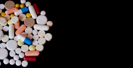 Pharmacy background on a dark table. Levitation pills. Tablets on a dark background which falling down. Pills. Medicine and healthy. Close up of capsules. Pills falling on black background, place for text.の写真素材