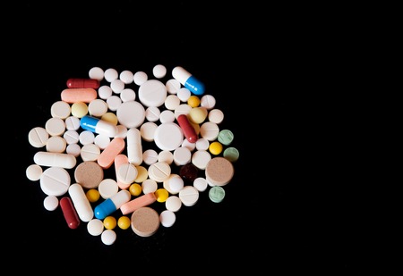 Pharmacy background on a dark table. Levitation pills. Tablets on a dark background which falling down. Pills. Medicine and healthy. Close up of capsules. Pills falling on black background, place for text.の写真素材