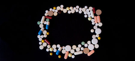 Frame of pills on a dark background with free space for text, top view.