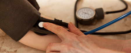 Cropped image of male doctor checking blood pressure of patient at table.の写真素材