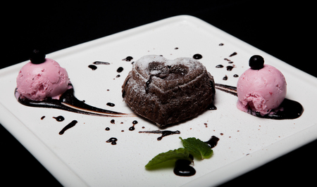 Dessert fondan chocolate with ice-cream on a white plate on a black background. Exquisite French chocolate dessert fondan.の写真素材