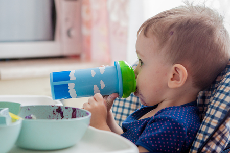 baby in the kitchen drinking juice or milk, vitamins and healthの写真素材