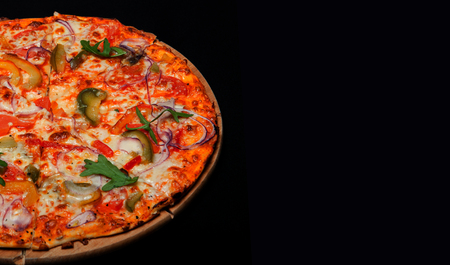 Pizza on a wood board on a black background.の写真素材