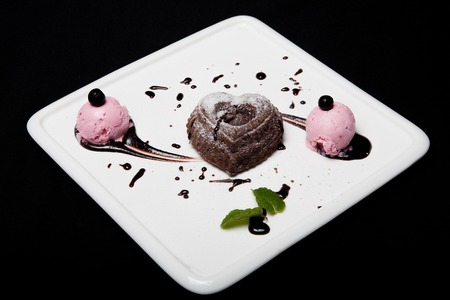 Dessert fondan chocolate with ice-cream on a white plate on a black background. Exquisite French chocolate dessert fondan.の写真素材