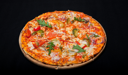 Pizza on a wood board on a black background.の写真素材