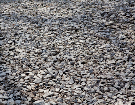 Texture of gray gravel. Grey stony floor. A wall of gray gravel. Stones small and medium-sized. Sharp edges of the stones. Sand and stones on the floor. The land is covered with stones.の写真素材