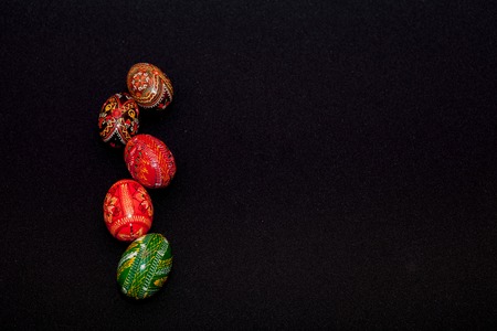 There is a pysanka with the traditional Ukrainian ornament in the black background. The Easter egg is divided and decorated with a pattern using a pencil before waxing.の写真素材