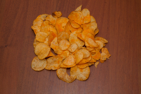 Potato chips on a wooden background, top view. Salty crisps scattered on a table.の写真素材