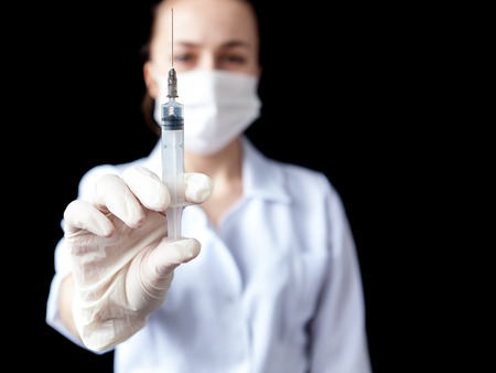 Blurred image of nurse holding syringe in hand on black background.の写真素材