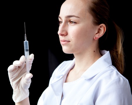 A medical doctor preparing an injection in a syringe.の写真素材