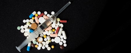 Pharmacy background on a dark table. Levitation pills. Tablets and syringe on a dark background. Pills. Medicine and healthy. Close up of capsules. Pills falling on black background, place for text.の写真素材