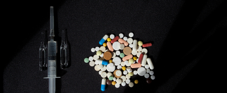 Pharmacy background on a dark table. Levitation pills. Tablets and syringe on a dark background. Pills. Medicine and healthy. Close up of capsules. Pills falling on black background, place for text.の写真素材