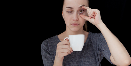 Hot drink A sleeping girl holding a cup of tea or coffee on a black background.の写真素材