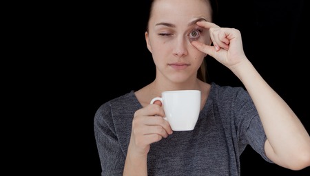 Hot drink A sleeping girl holding a cup of tea or coffee on a black background.の写真素材