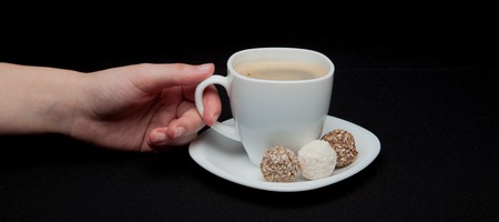 The hand holds coffee on a black background. Top view of copyspace for your text.の写真素材