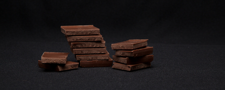 Chocolate blocks stack on black background, copyspace for your text.の写真素材