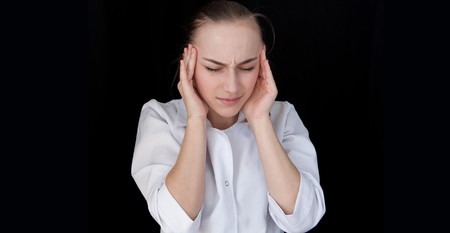 Front view of a young intellectual doctor on a black background with text space. The medical worker has a headache.の写真素材