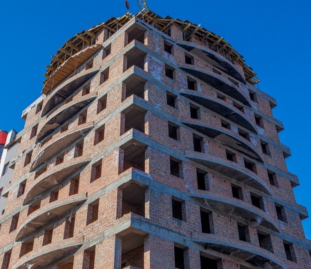 Construction site of a new apartment high building against blue sky. House to plaster. Residential area development. Real estate project growth concept.の写真素材