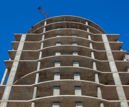 Construction site of a new apartment high building against blue sky. Residential area development. Real estate project growth concept.の写真素材