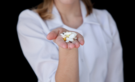 Front view of a young intellectual doctor on a black background with text space. The medical worker provider offers a pillの写真素材