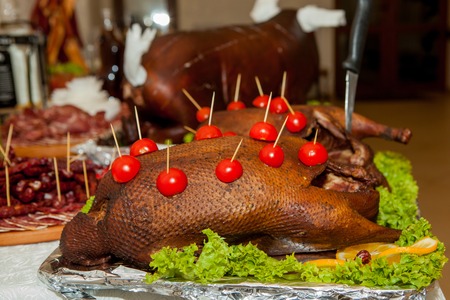Garnished roasted turkey on holiday table decorated tomatoes.の写真素材
