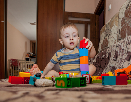 Sweet little boy building tower from cubes at home.の写真素材
