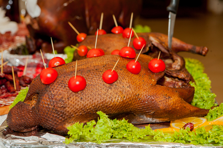 Garnished roasted turkey on holiday table decorated tomatoes.の写真素材