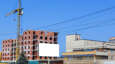Construction site of a new apartment high building with tower cranes against blue sky. Bikeboard on the background of a new building. Residential area development. Real estate project growth concept.の写真素材